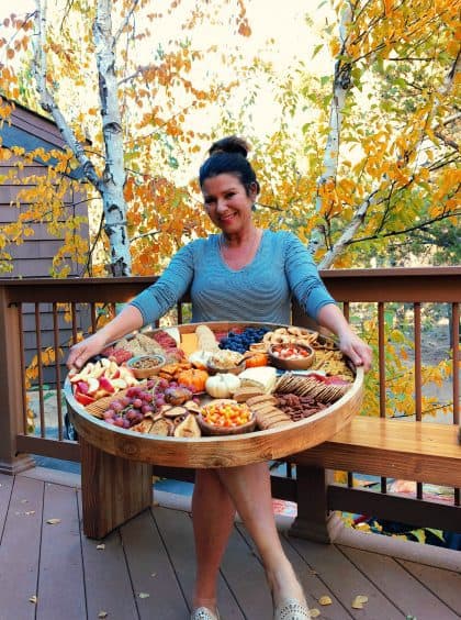 woman holding a charcuterie board outside in fall colors