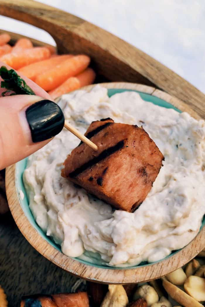 dipping spam bite on an Epic Retro SPAM Charcuterie Board