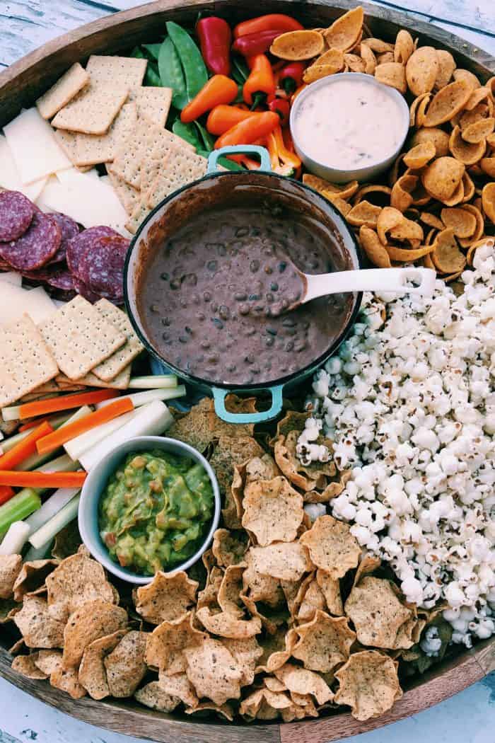 black bean dip in the center of a game day board with snacks