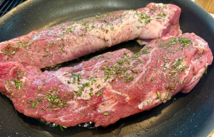 adding pork to saute pan with oil