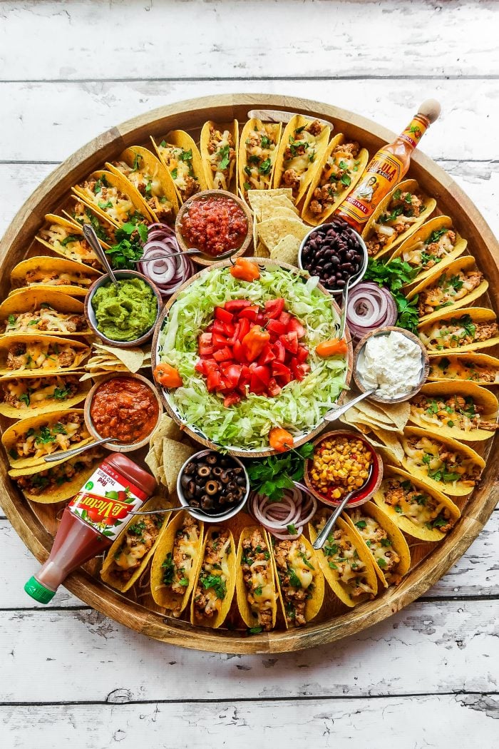large round platter surrounded with tacos and toppings