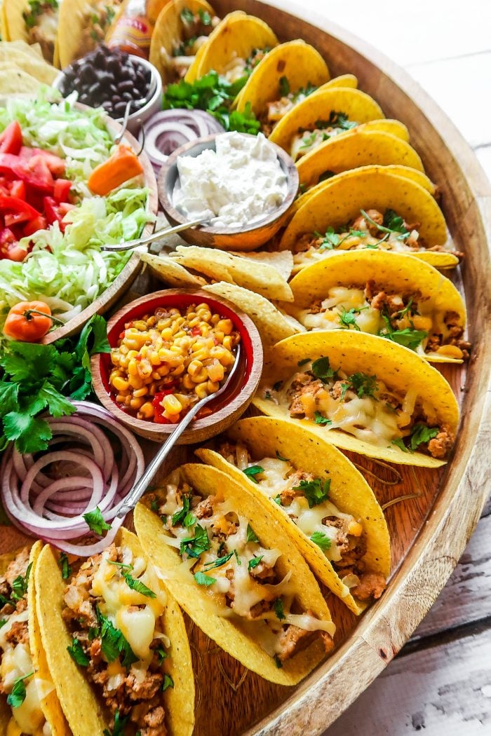 large round platter surrounded with tacos and toppings