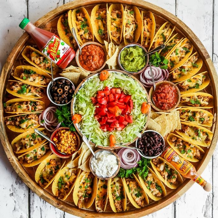 large round platter surrounded with tacos and toppings