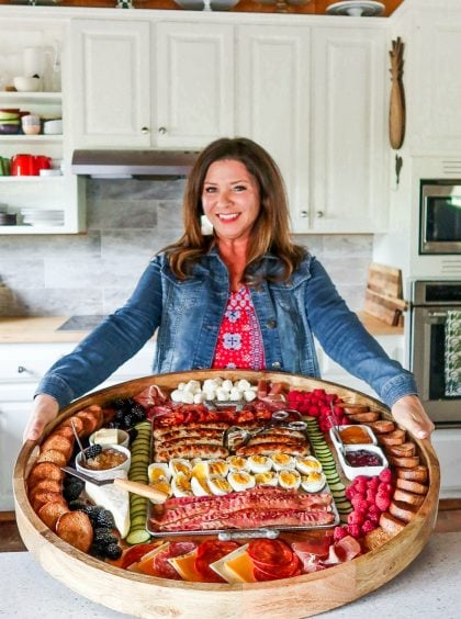 woman holding a round, epic charcuterie breakfast board