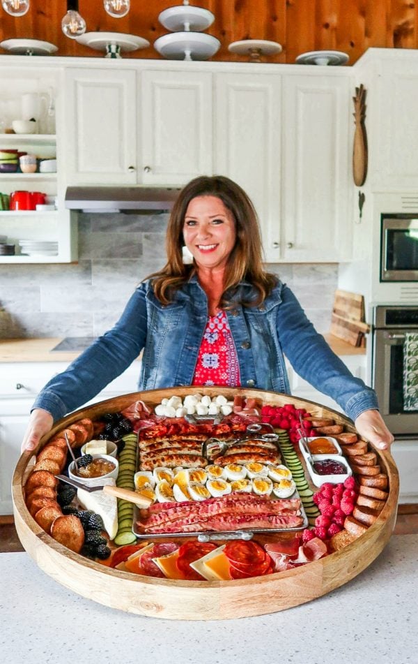 woman holding a round, epic charcuterie breakfast board