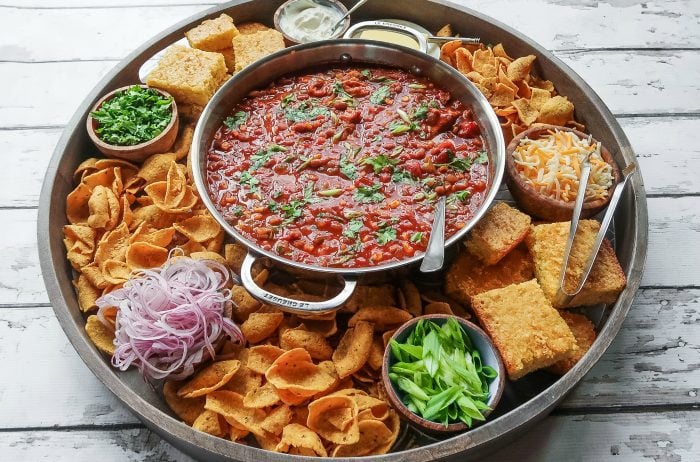 large platter with bowl of salsa in the middle surrounded by various chips and crackers