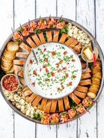 clam chowderin a big pot, on a round board with bread and shrimp cocktail cups