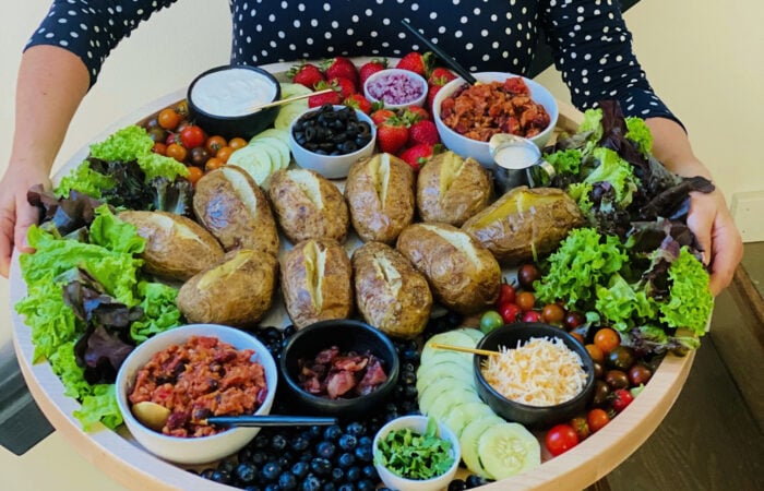 holding a big board with russed potatoes that are baked