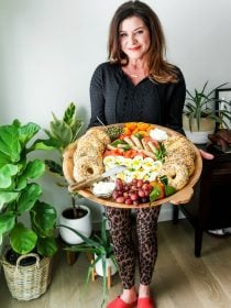 a lady holding a breakfast board with lox and bagels