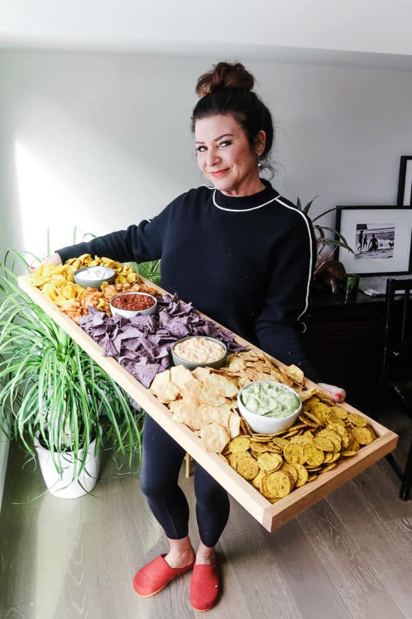 woman holding a large board of chips and salsa