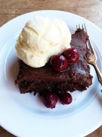piece of chocolate cake with cherries on top with ice cream