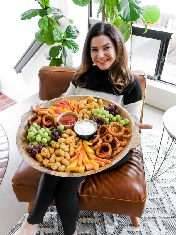 woman holding a tater tots board full of snacks