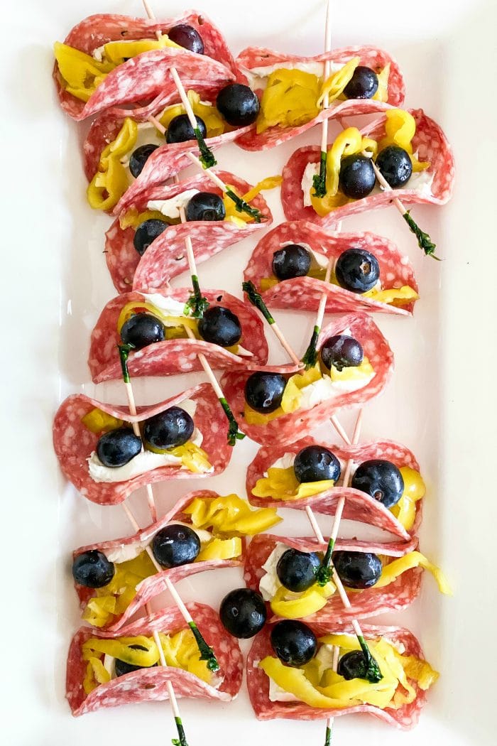 13 salami pepperoncini rollups on a white platter