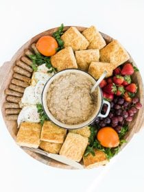 a beautiful board filled with pork gravy, buttermilk biscuits, fried eggs, sausage, and fruit