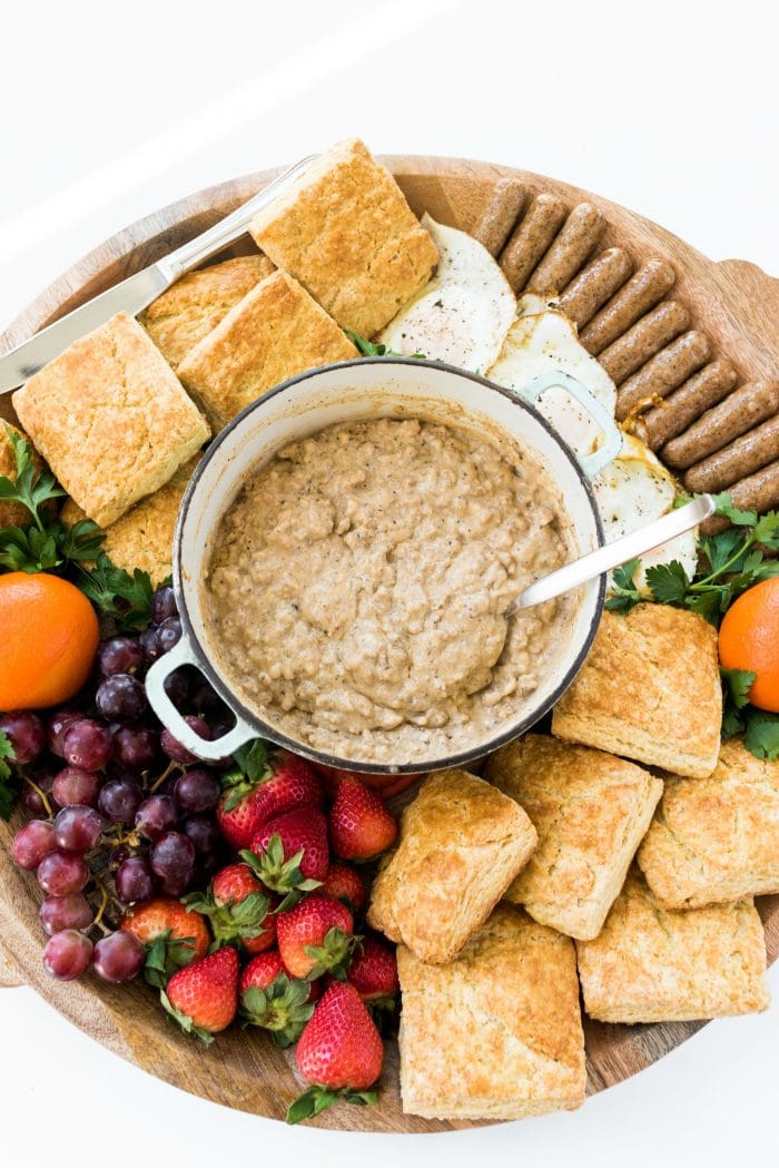 a round food board filled with biscuits and gravy and fresh fruit