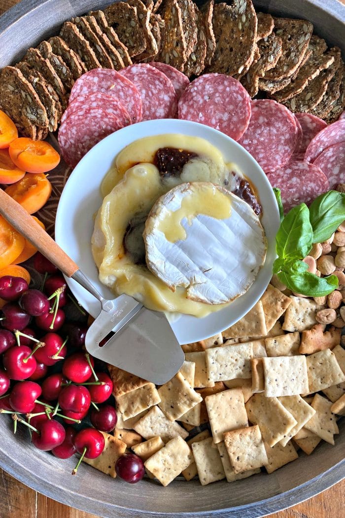 center plate of warm brie cheese with chili fig, with crackers, nuts, and apricots