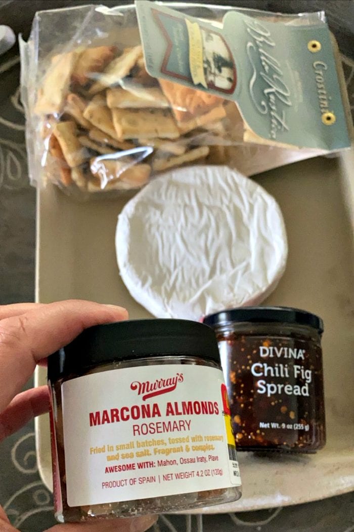 jar of chili fig spread and marcona almonds, with a round of uncooked brie cheese