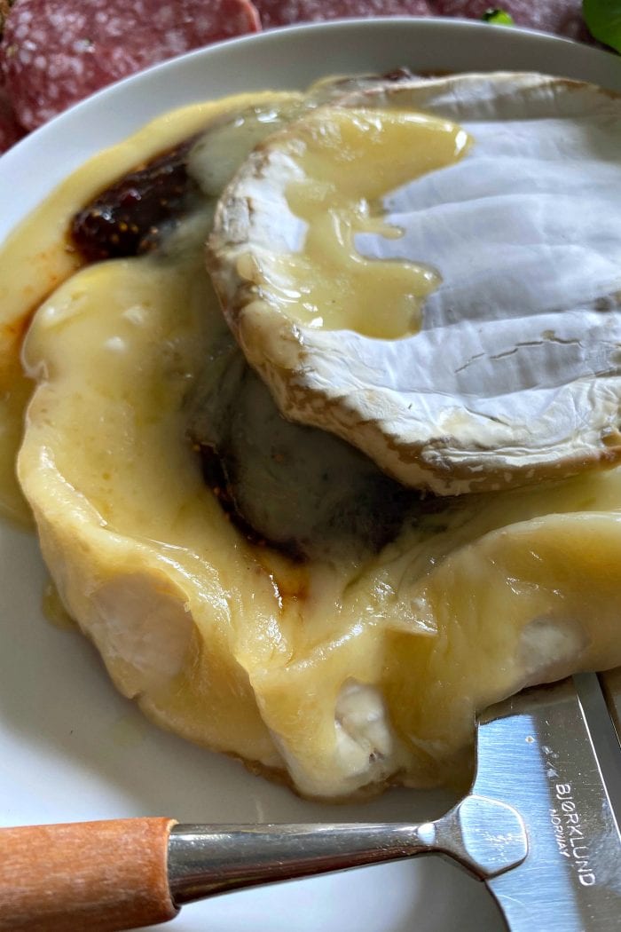 close up of warm brie cheese with chili fig jam in the center