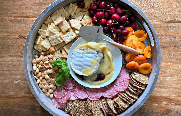 brie cheese board with fruit, nuts, and crackers