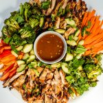 a platter of chicken thighs cut into strips with veggies, and dip in a bowl in the center