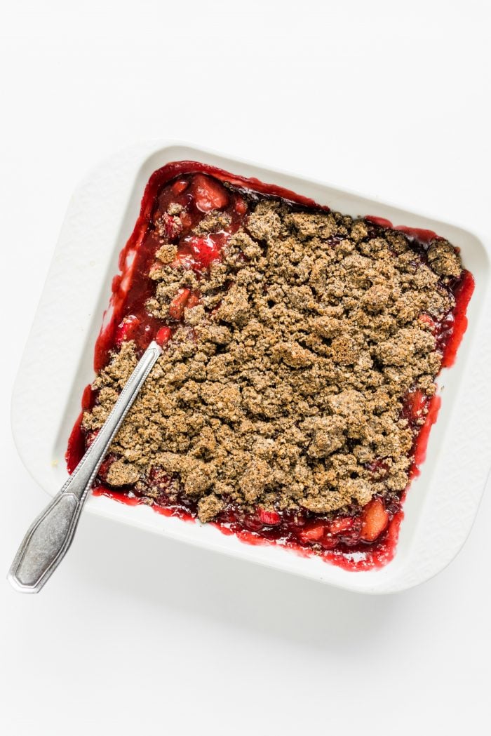 white square baking dish with poppyseed crisp topping over strawberries and rhubarb
