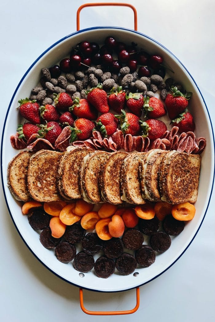 a tray with grilled cheese sandwiches and fresh fruit and chocolate brownies and almonds