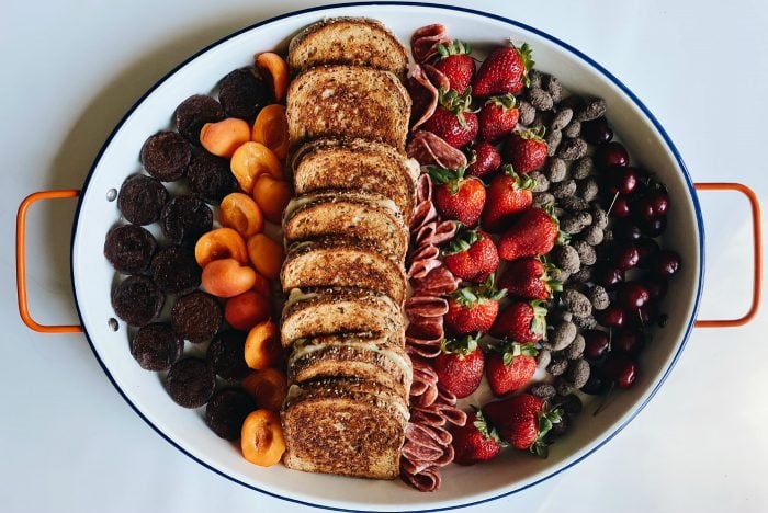 a tray with grilled cheese sandwiches and fresh fruit