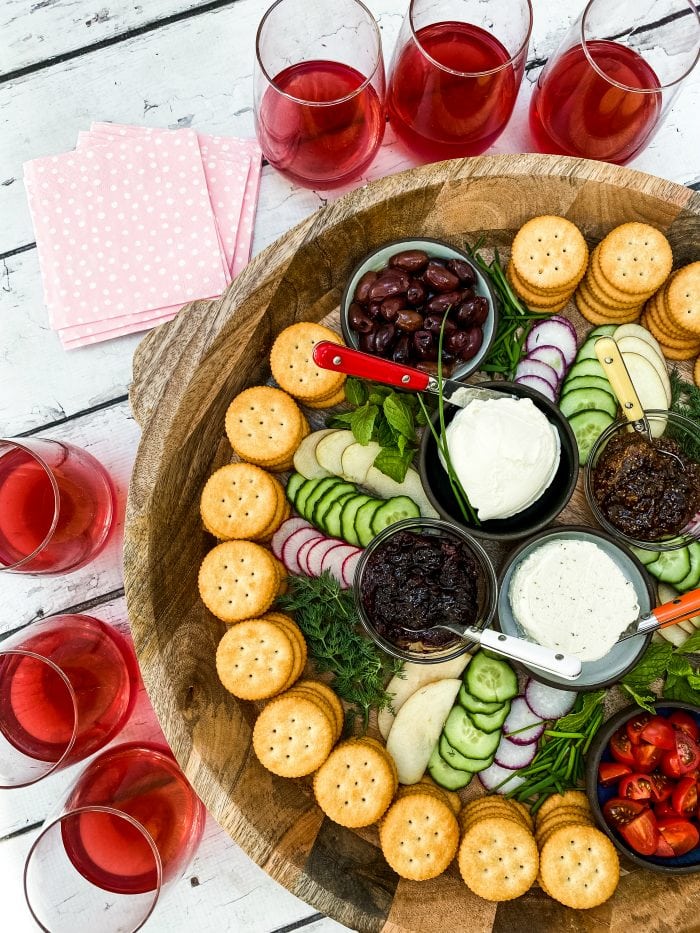 round tray of crackers and cheese snacks with red drinks