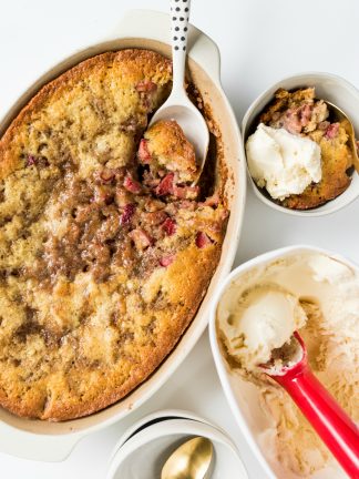 lookng down on a rhubarb strawberry cobbler with a side serving, and scoop of vanilla ice cream