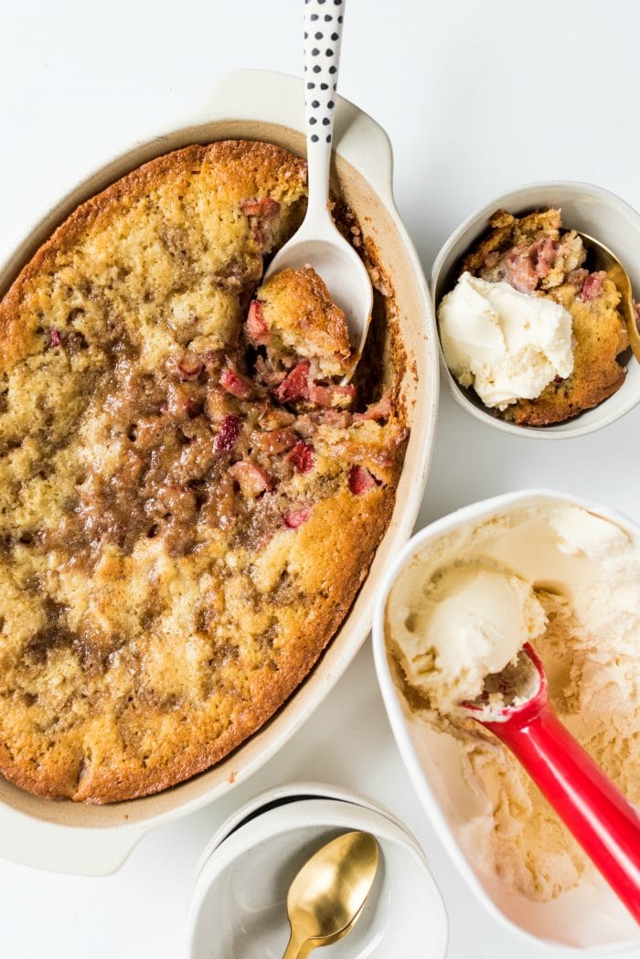 lookng down on a rhubarb strawberry cobbler with a side serving, and scoop of vanilla ice cream