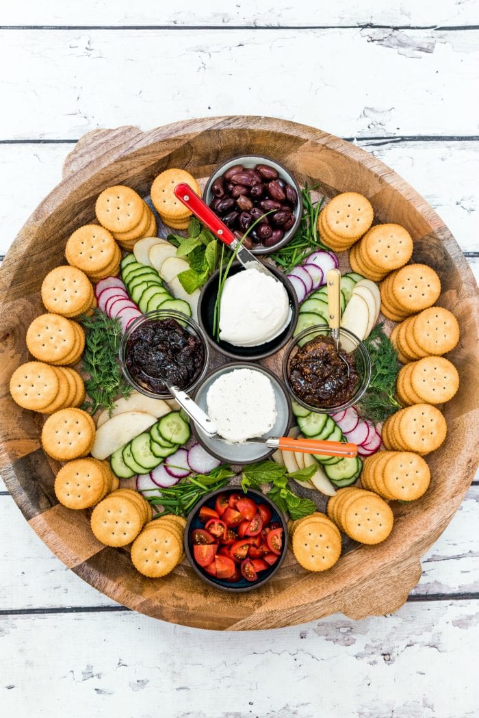 round platter of soft cheese, veggies, and jam with Ritz crackers