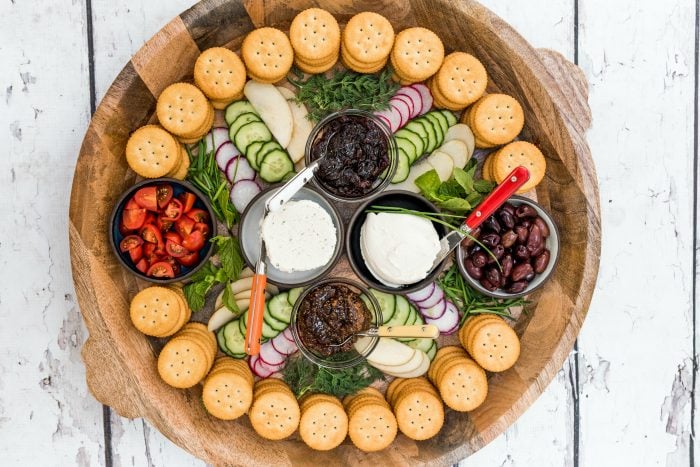 round tray of crackers, cheese, veggies, and jam