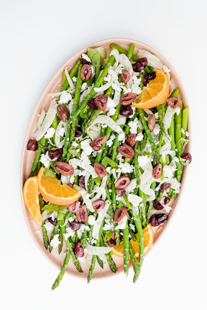 pink oblong plate with asparagus and fennel salad, garnished with orange slices