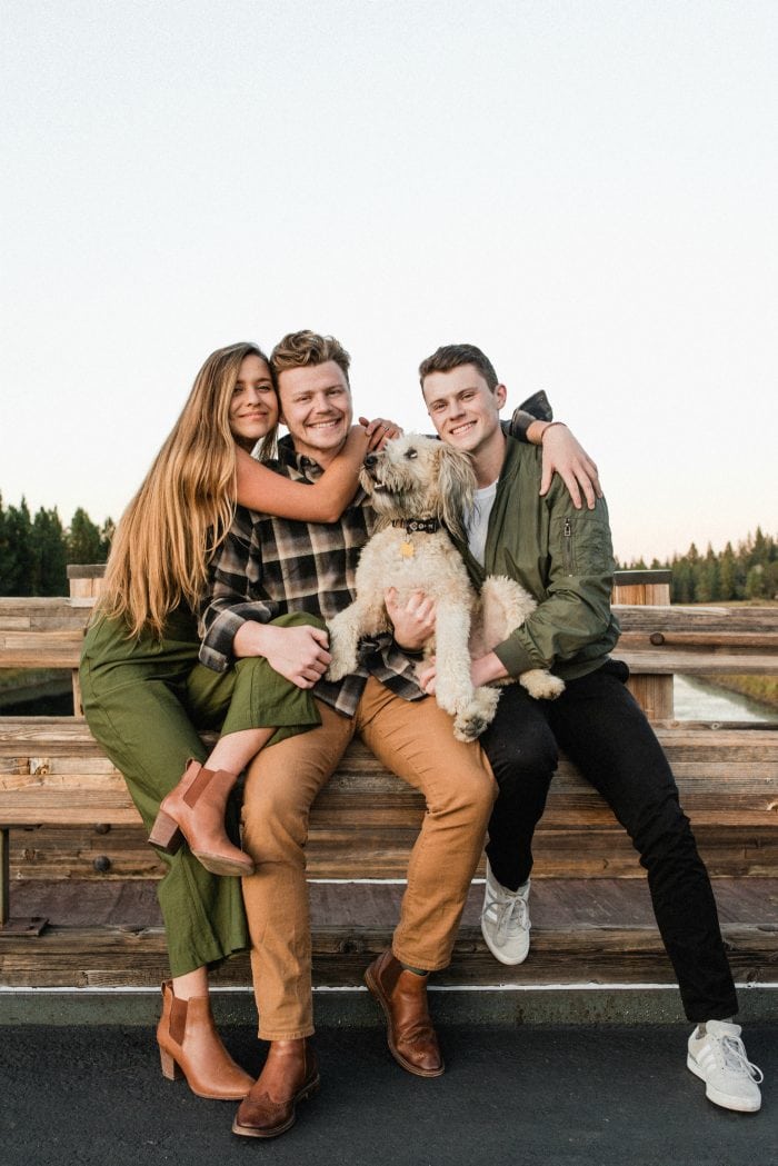 kids holding dog sitting on a bridge