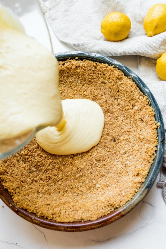 pouring lemon pie filling into a Ritz cracker crust