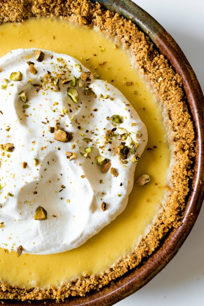 fresh whipped cream and pistachio nuts chopped on a ricotta lemon pie