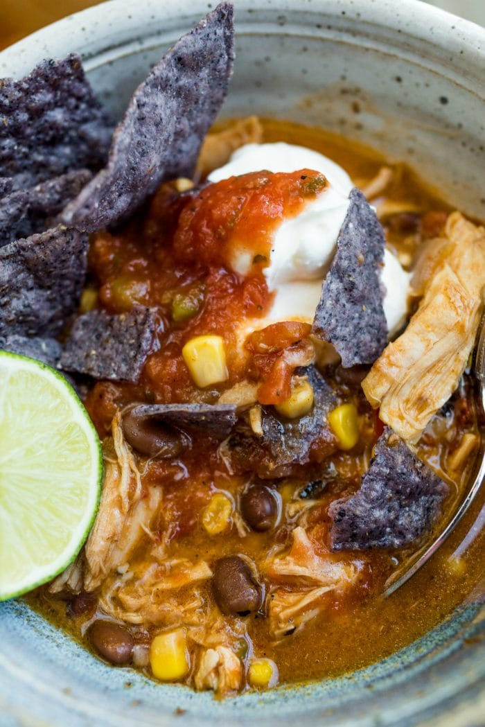 close up small bowl of chicken tortilla soup with sour cream, chips, and salsa