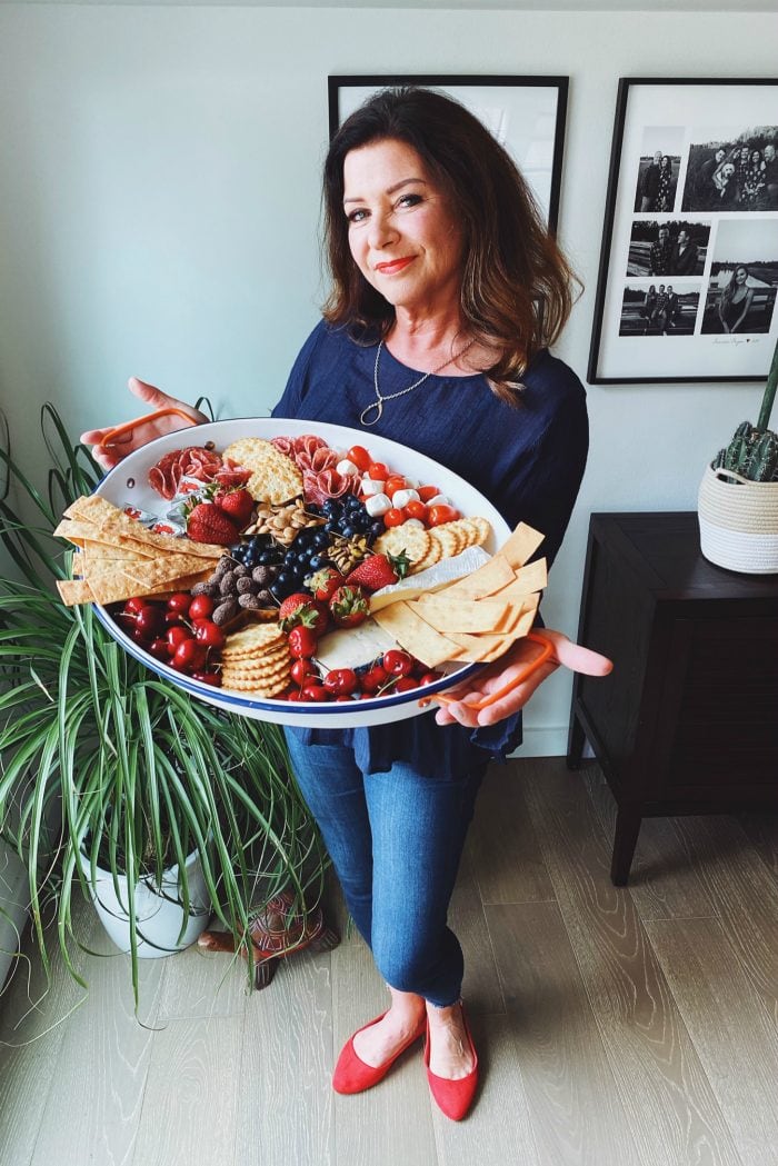 woman holding an oval tray with cheese and crackers and fruit for the 4th of July