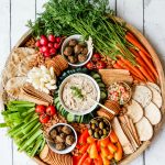 large round platter with vibrant veggies cut up, cashew dip, vegan meatballs, and more