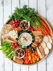 large round platter with vibrant veggies cut up, cashew dip, vegan meatballs, and more