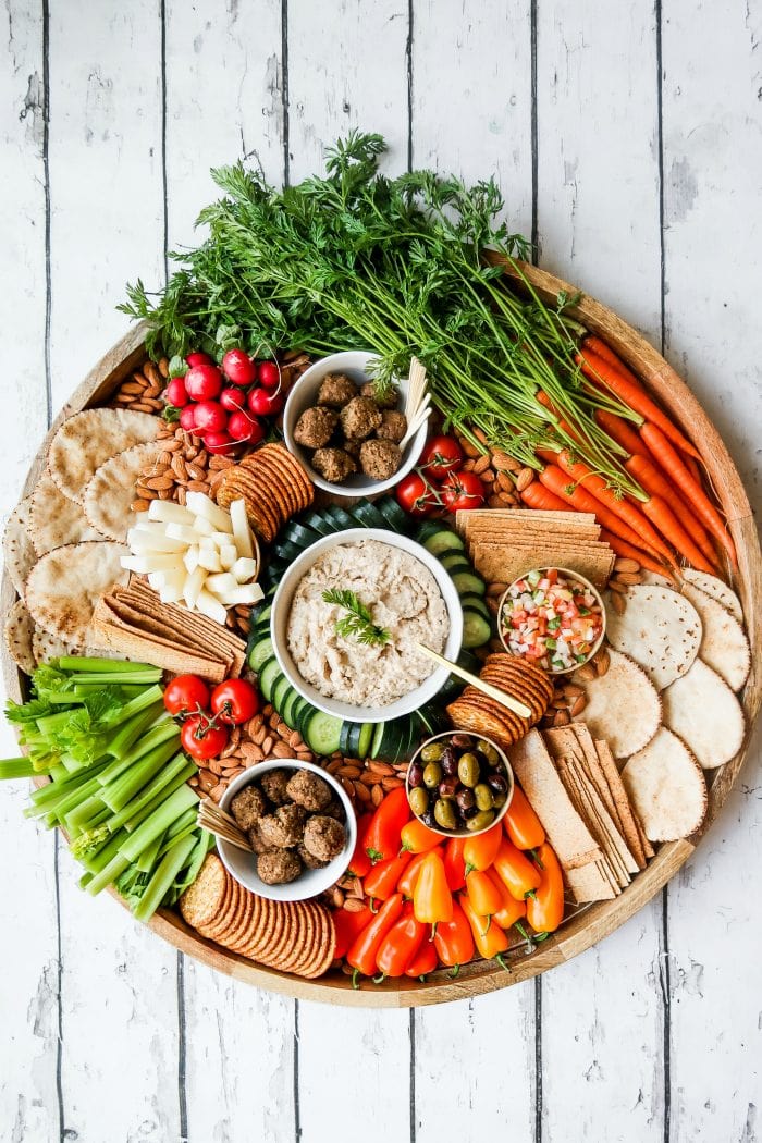 large round platter with vibrant veggies cut up, cashew dip, vegan meatballs, and more