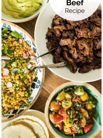 taco spread with shredded beef, corn salad, salsa, tortillas, and green sauce