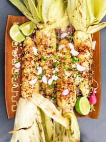 plate of charred grilled corn on the cob (with husks)