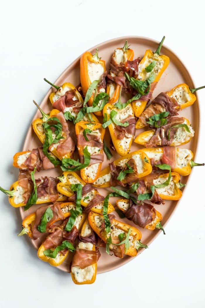 appetizer plate of Prosciutto-Wrapped Mini Peppers garnished with fresh basil strips