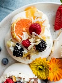 a mini pavlova with lemon curd, orange slice, berries, and coconut