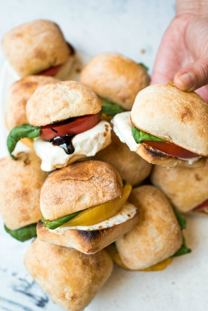 a platter of caprese sliders with heirloom tomatoes