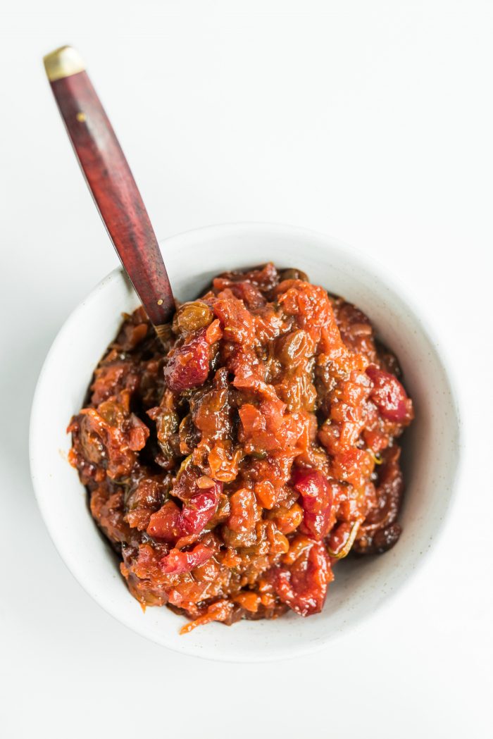 white bowl of cherry apricot chutney with a wood spoon