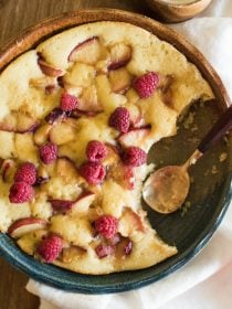 a round peach butter cake with raspberries on top