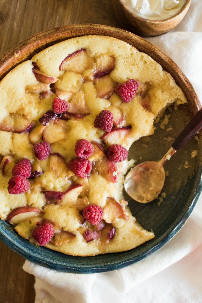 a round peach butter cake with raspberries on top
