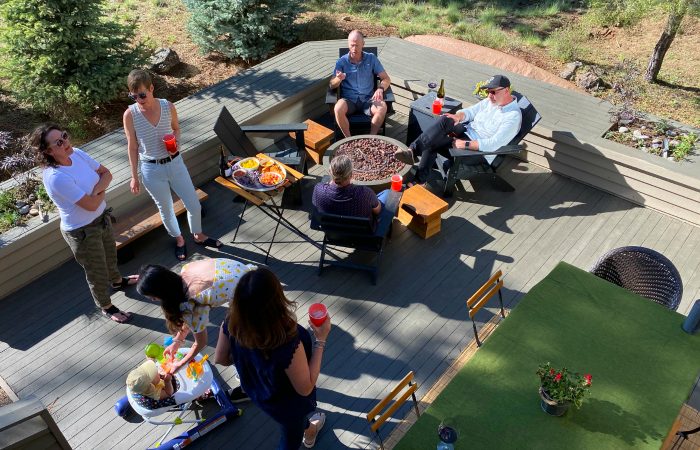 outdoor entertaining space with 6 people standing and sitting with drinks